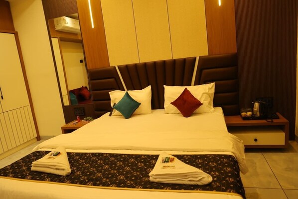 A hotel room with a large bed, a nightstand, a mirror, and a wooden headboard.