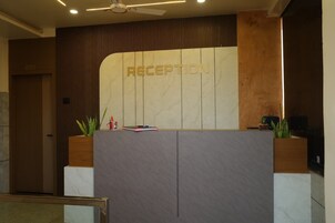 Un mostrador de recepción con un cartel que dice 'RECEPTION', un ventilador de techo y una puerta con el número '201'.