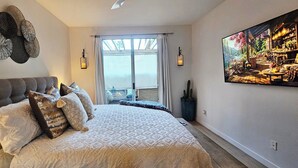 Un dormitorio con una cama grande, vistas por la ventana y un cuadro en la pared.