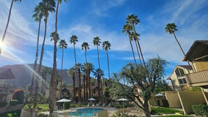 Un resort con piscina, palmeras y montañas al fondo.