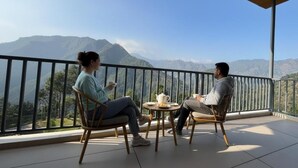Un balcón con dos sillas y una mesa, con vistas a un paisaje montañoso.