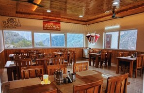 A restaurant with wooden furniture, large windows, and a ceiling fan.