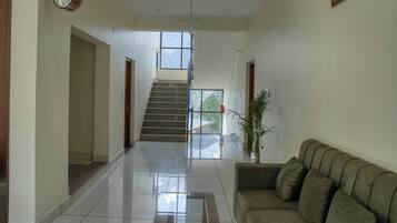 Un couloir avec un escalier, une table basse en verre et un canapé.