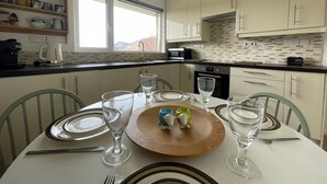 Une table à manger dressée avec des assiettes, des verres et une planche en bois ornée de petites figurines d’animaux en céramique.