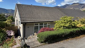 Une maison avec un toit en pente, une porte d’entrée et un petit porche.