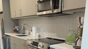 A modern kitchen with stainless steel appliances, a microwave, and a green toaster. - Luxurious West Hollywood apartment (West Hollywood)