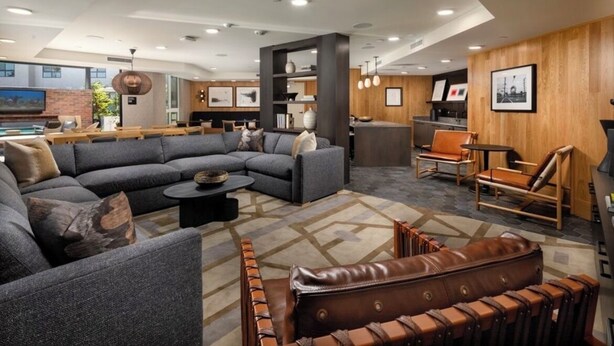 A modern hotel lobby with a large sectional sofa, leather armchairs, a bar area, and a dining space. - Luxurious West Hollywood apartment (West Hollywood)