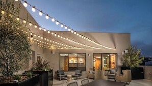 An outdoor patio area with a dining table and chairs, string lights, and potted plants. - Luxurious West Hollywood apartment (West Hollywood)