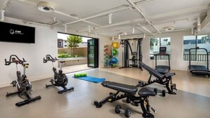 A gym with exercise equipment, a television, and a view of the outdoors. - Luxurious West Hollywood apartment (West Hollywood)