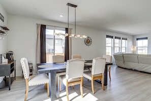 A modern living room with a dining table, chairs, a sofa, and a chandelier. - WFH-Friendly Commerce City Home Near DIA (Commerce City)