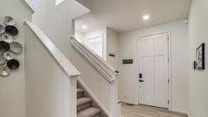 A staircase with a handrail, a door with a sign, and a wall-mounted light fixture.