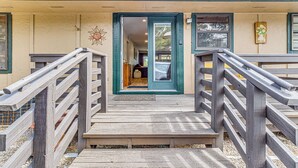 Eine hölzerne Treppe führt zum Eingang eines Gebäudes mit einer Tür, einer kleinen Veranda und einer Sonnendekoration an der Wand.