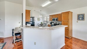 Una cocina amplia con armarios de madera, una isla de mármol y un comedor con mesa y sillas.
