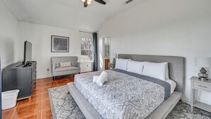 Un dormitorio con cama, ventilador de techo, cómoda, silla y ventana.