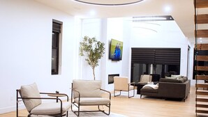 A modern living room with a sofa, two armchairs, a coffee table, and a fireplace. - Grand, Spacious Villa in the Heart of Downtown High River (High River)