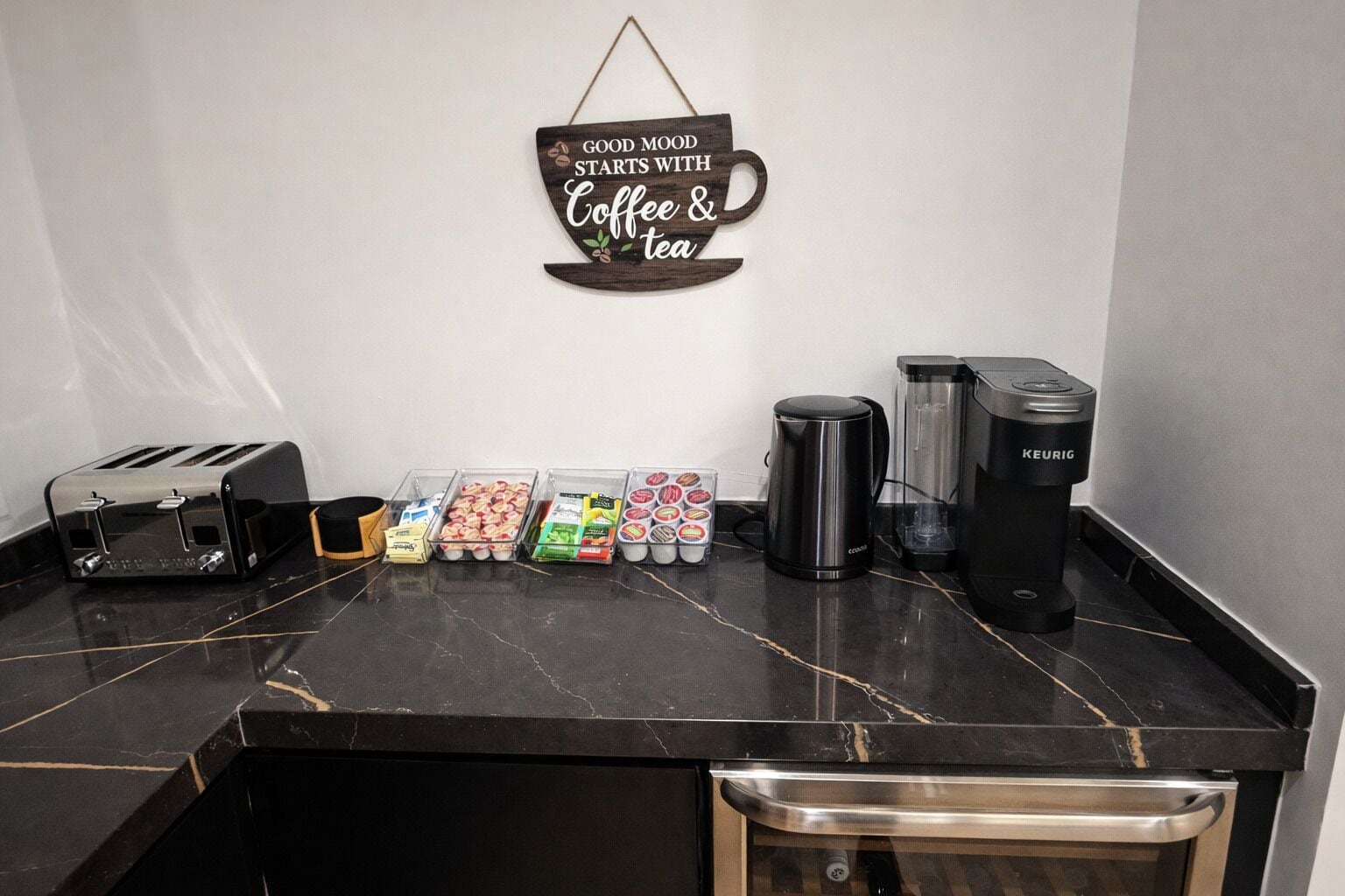 A kitchen counter with a coffee maker, toaster, and containers of snacks.