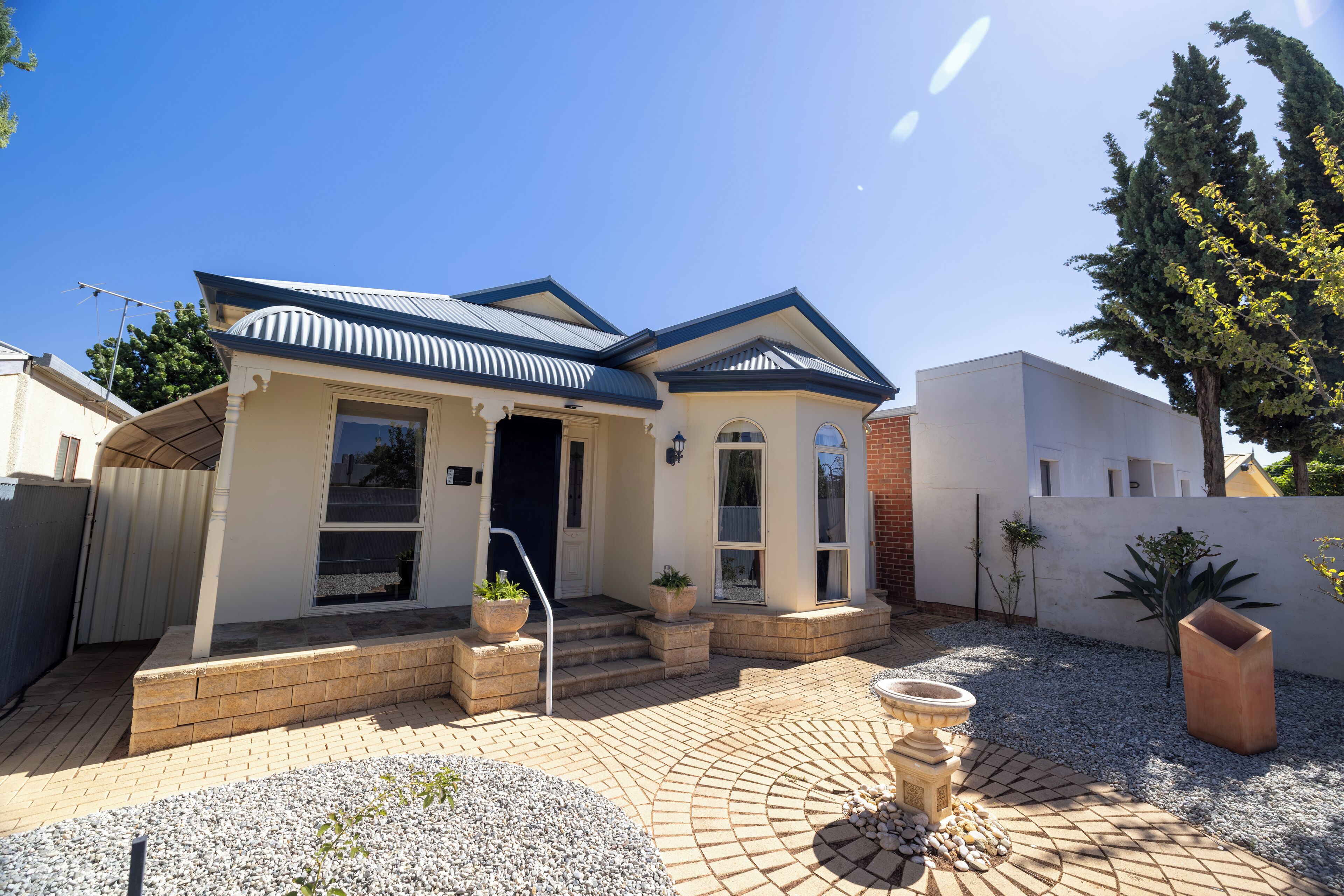 A residential house with a brick exterior, a tiled patio, and a garden area with a fountain.