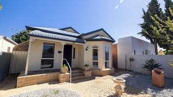 A residential house with a brick exterior, a tiled patio, and a garden area with a fountain.