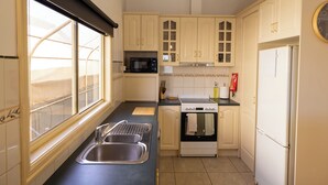 Una cucina con un lavello doppio, un forno a microonde, un forno e un frigorifero.