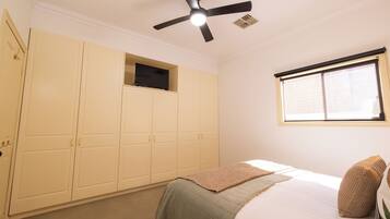 A bedroom with a bed, a ceiling fan, a window, and a wardrobe.