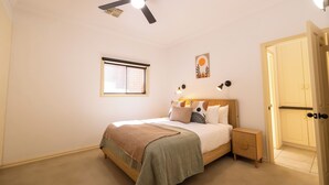 Una camera da letto con un letto, un comodino, una ventola a soffitto, una finestra e una porta.