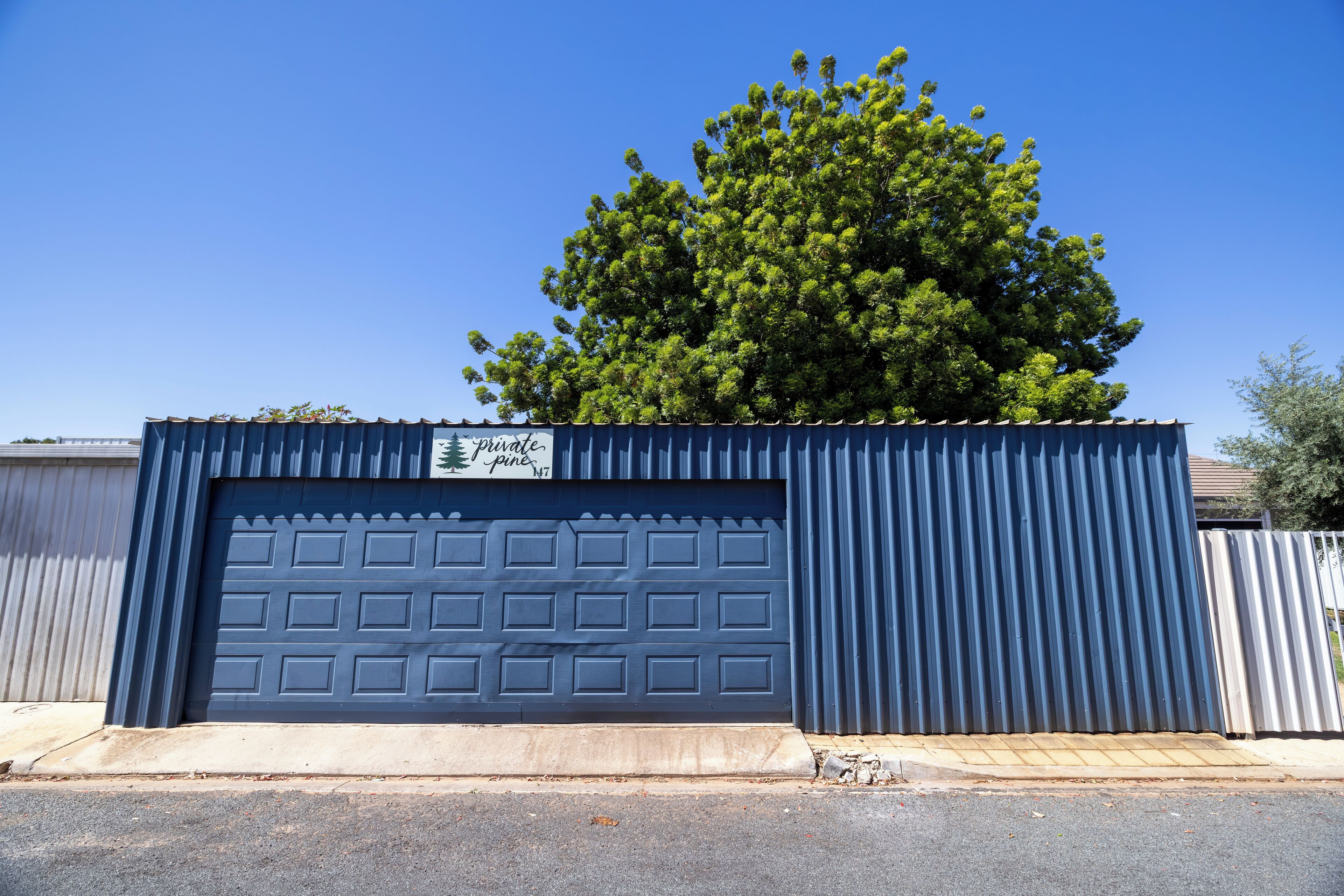 Puerta de garaje azul con un letrero que dice 'private pine'.