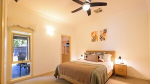 Una camera da letto con un letto, comodini, una ventola a soffitto e una finestra.