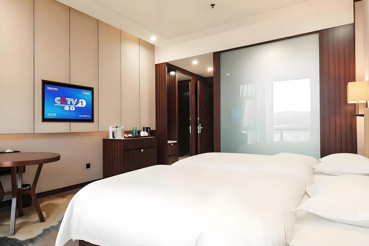 A hotel room with a bed, a desk, a TV, and a wardrobe.