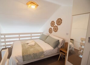 A bedroom with a bed, a bedside table, a mirror, and wall decor.