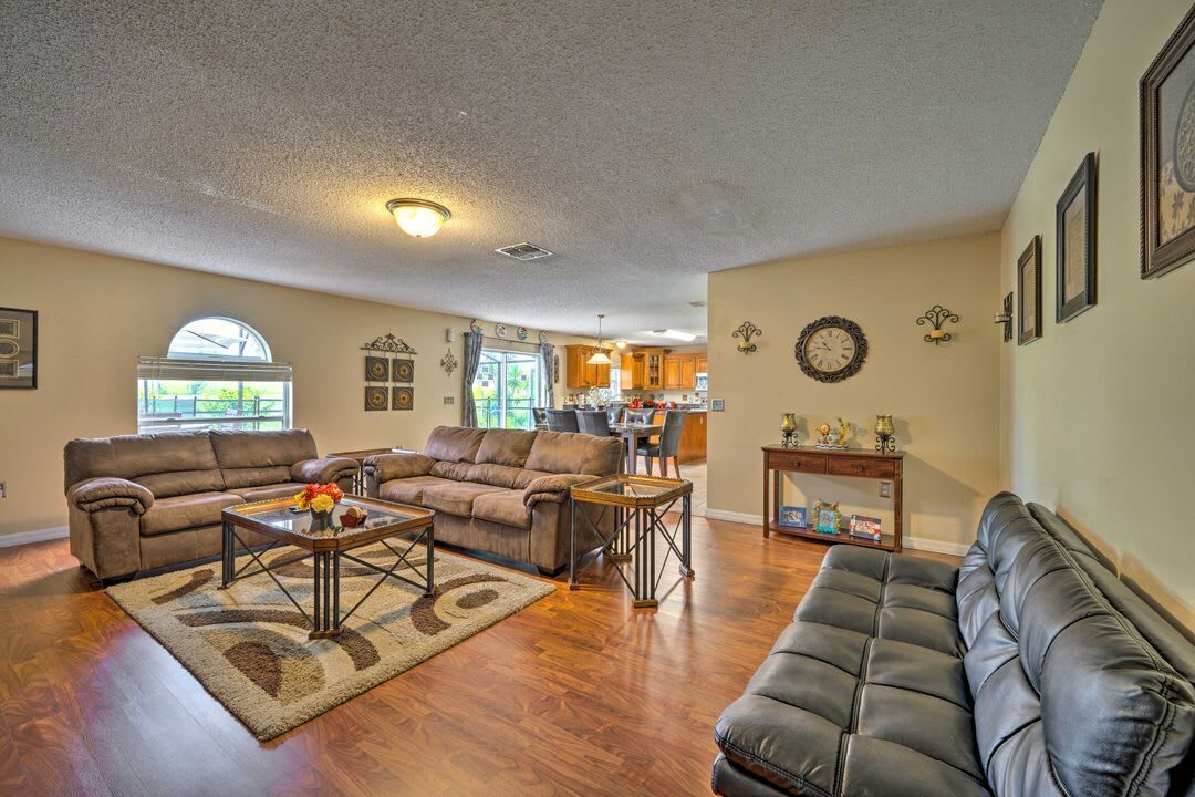 A spacious living room with a sofa, coffee table, and a dining area in the background.