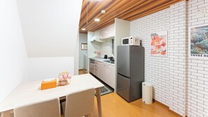A compact kitchen with white brick walls, a wooden ceiling, and a dining area with a table and chairs. - Recommended for USJ, Osaka Sight Seeing,Newly Reno! 5min walk to station. 2bed (Osaka)