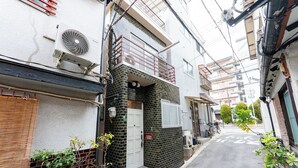 A narrow urban street with residential buildings, a white door, and a small step leading to a balcony. - Recommended for USJ, Osaka Sight Seeing,Newly Reno! 5min walk to station. 2bed (Osaka)