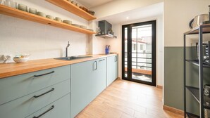 Eine Küche mit hellblauen Schränken, Holzböden und einer schwarzen Tür zu einem Balkon.