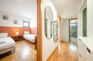 Une chambre d’hôtel avec deux lits, une table de chevet avec une lampe, un grand miroir et une armoire.