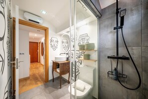 Une salle de bain moderne avec une douche à parois de verre, un lavabo blanc et des œuvres d’art décoratives sur les murs.