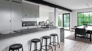 Una cocina moderna con una isla central, taburetes de bar y un comedor con mesa y sillas.