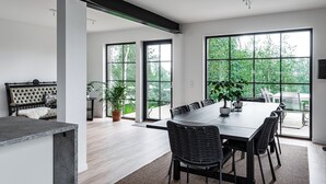 Un comedor moderno con una mesa grande, sillas negras y vistas amplias a través de ventanas.