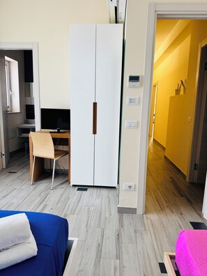 Habitació d'hotel amb un llit, escriptori, armari i televisió.