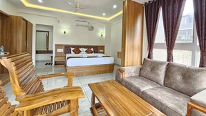 A hotel room with a bed, sofa, wooden furniture, and a ceiling fan. - Navarathna Comforts (Madikeri)