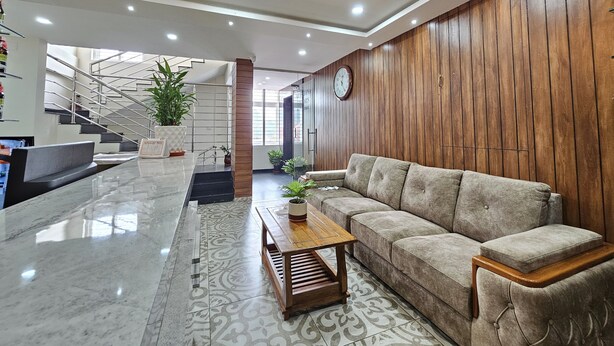 A modern living room with a sofa, coffee table, and decorative lighting. - Navarathna Comforts (Madikeri)