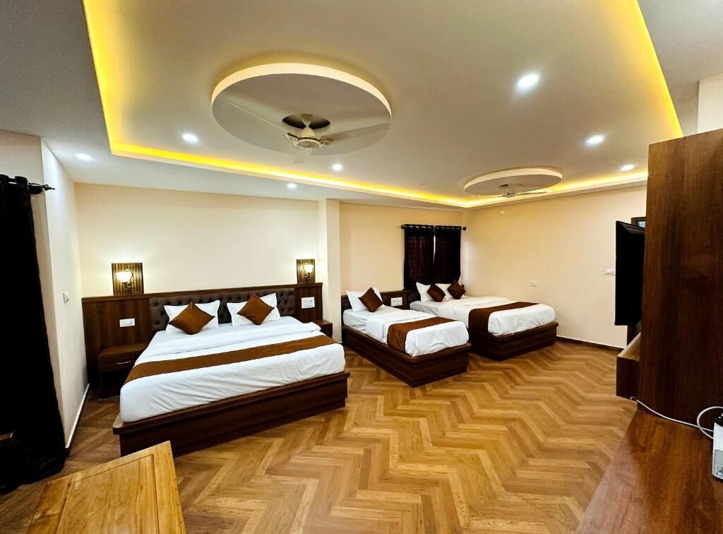 Une chambre d  ’hôtel avec trois lits, un plancher en bois, un ventilateur de plafond et des luminaires encastrés.