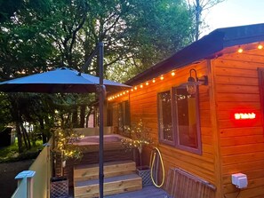 Une cabane en bois avec une véranda, des marches et des guirlandes lumineuses.