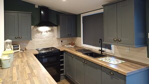 Una cocina moderna con gabinetes grises, una estufa negra y una encimera de madera.