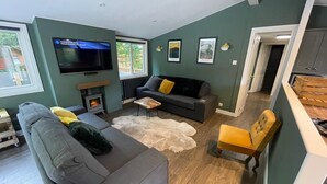 Una sala de estar con sofá, una mesita, televisor y chimenea.