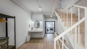A modern interior with a staircase, a bathroom with a mirror, and a wooden floor. - Industrial Loft Sukhumvit 3-Bedroom Designer House - 2 Min to BTS Bang Chak (Krung Thep Maha Nakhon)