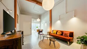 A modern living room with a TV, sofa, and dining area. - Industrial Loft Sukhumvit 3-Bedroom Designer House - 2 Min to BTS Bang Chak (Krung Thep Maha Nakhon)