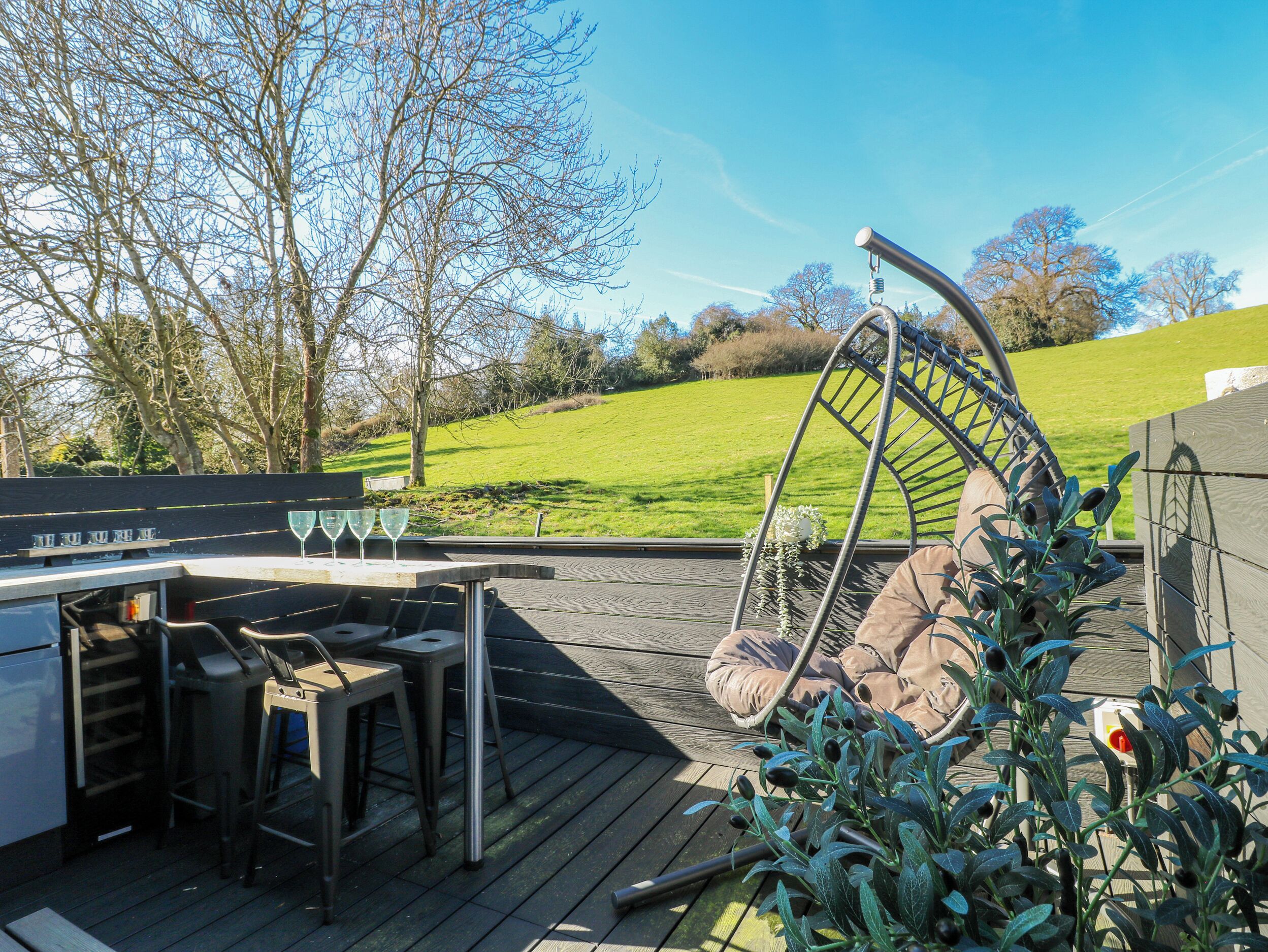 An outdoor deck with a barbecue area, seating, and a hanging chair.