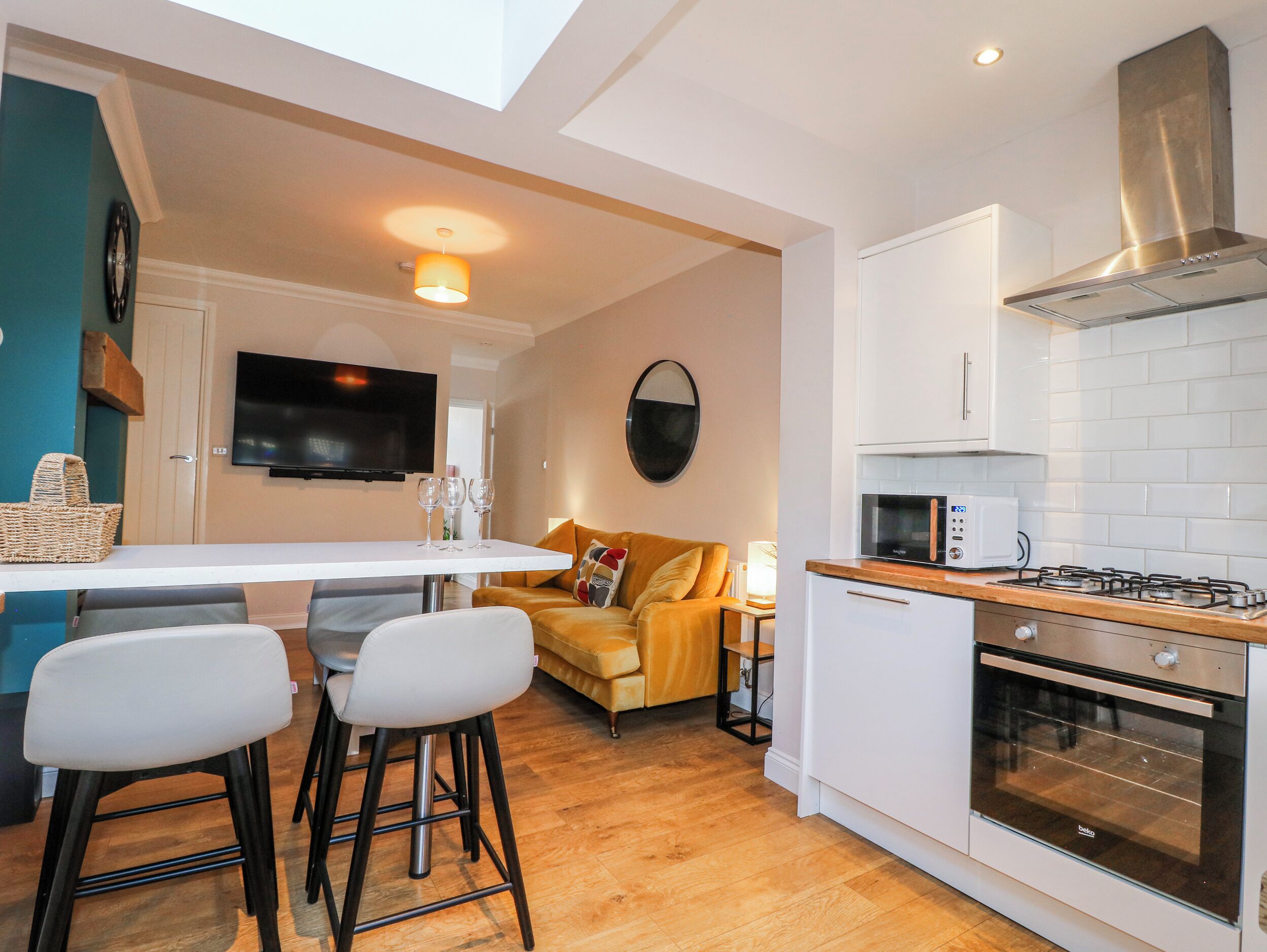 A compact kitchen with a dining area, a sofa, and a TV.