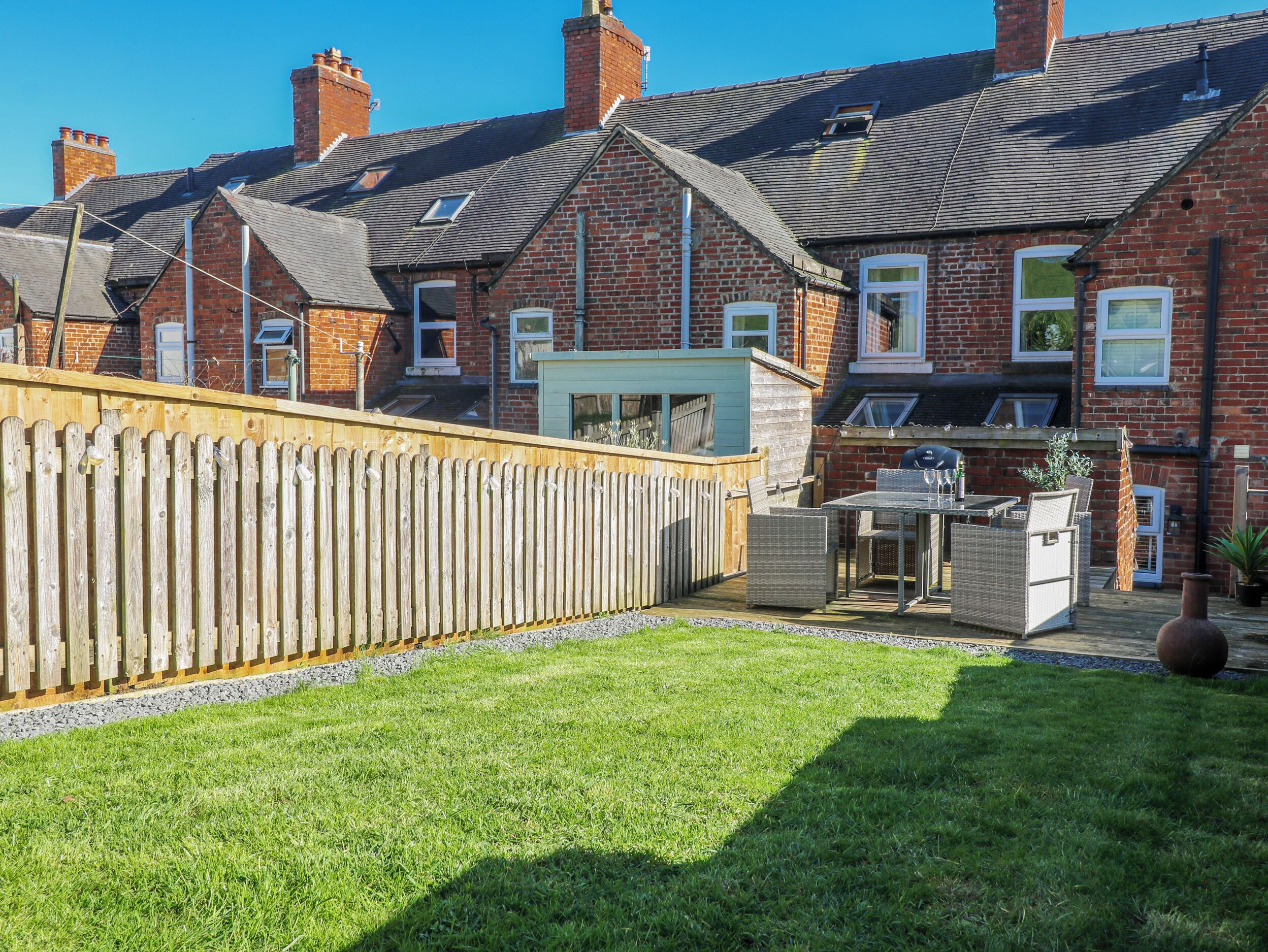 A residential area with brick houses, a wooden fence, and a grassy yard.