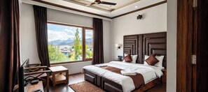 A bedroom with a large window, a bed, a desk, and a ceiling fan. - Hotel LA Park (Leh)